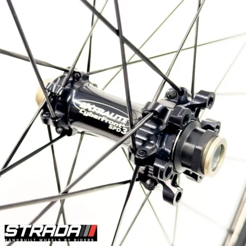 A picture showing a black Extralite SPD3+ bicycle hub laced to a Strada Performance Aero Disc brake 55 Ultra Gloss carbon front bicycle wheel.