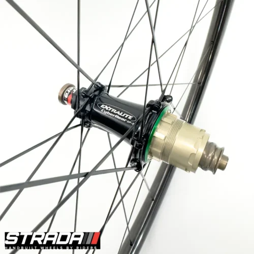 A picture showing a black rear extralite bicycle hub laced to a Strada Performance Aero Rim brake carbon rear bicycle wheel.