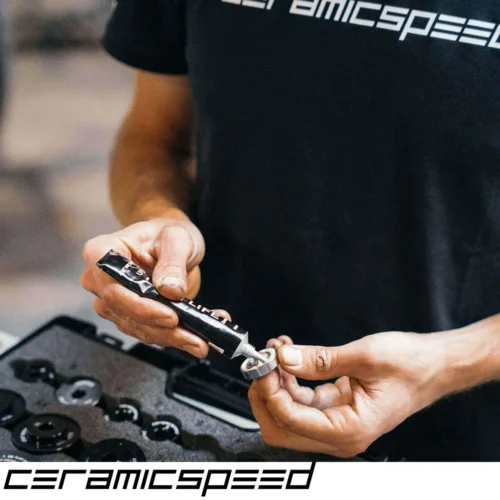 A picture showing a bike mechanic in a black t-shirt preparing a ceramicspped bearing for installation