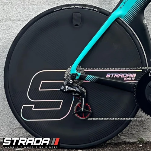 A picture showing a carbon Strada Ultra TT Disc disc Brake rear wheel in a raw carbon finish with a custom Strada S shape logo attached to a Cervelo P5 Time Trail Bicycle in Black and Light Teal.