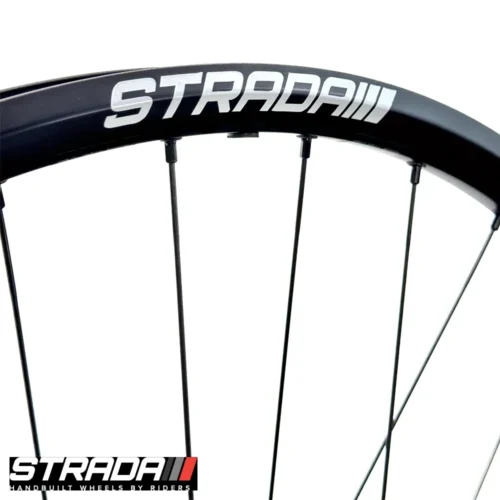 A picture showing a close-up of balck aluminium rim of a Strada Big Fella Gravel Disc bicylce wheel with a white strada logo.